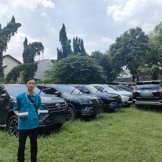 Teknisi gpssupertrack berseragam di depan deretan mobil pribadi pelanggan